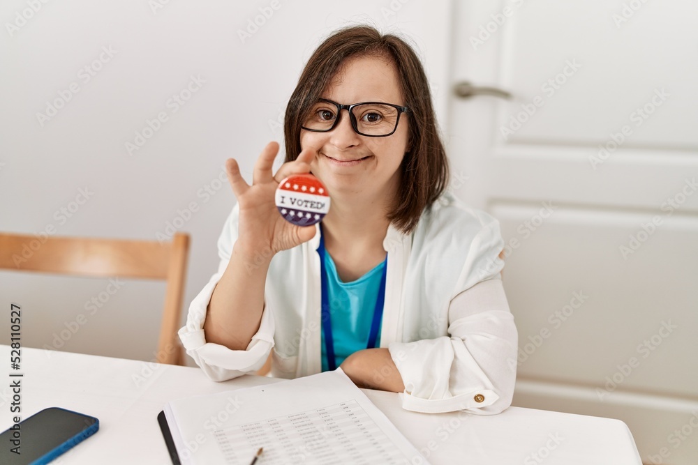 Brunette woman with down syndrome smiling holding vote badge at election room Brunette woman with down syndrome smiling holding vote badge at election room