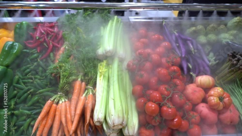 Grupo de vegetales frescos expuestos en una frutería con nebulización para frutas y verduras. photo