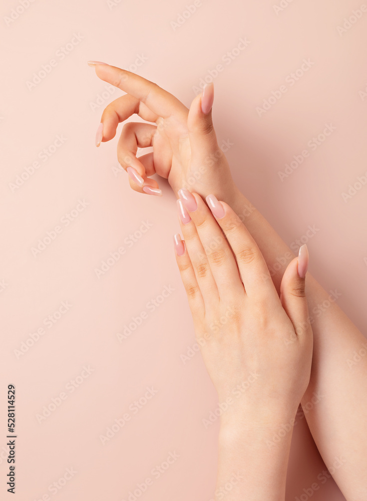Hands of a young woman with nude manicure, clean skin. Light pink nails with gel polish. Beauty care, treatment, salon concept. Nail design Hands of a young woman with nude manicure, clean skin. Light pink nails with gel polish. Beauty care, treatment, salon concept. Nail design