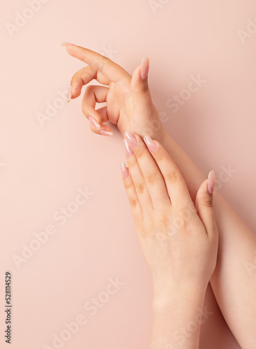 Hands of a young woman with nude manicure  clean skin. Light pink nails with gel polish. Beauty care  treatment  salon concept. Nail design