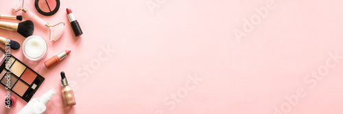 Makeup professional cosmetics on pink background. Cream, lipstick, shadow and brushes. Long banner format.
