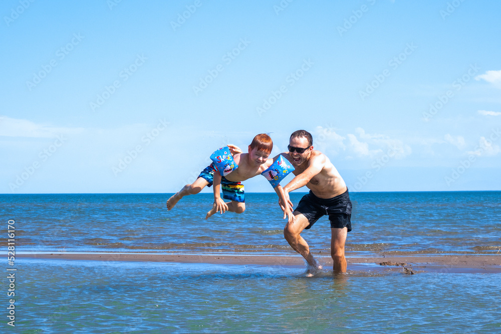 dad at sea throws his son into the water. fun on the water. happy summer dad at sea throws his son into the water. fun on the water. happy summer