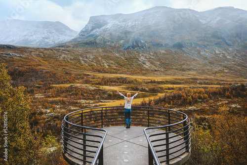 Woman enjoying autumn landscape on Vegaskjelet viewpoint travel outdoor aerial view forest and mountains tourist raised hands sightseeing in Norway photo