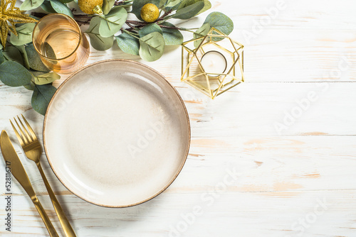 Christmas table setting with eucalyptus leaves and luxury metallic golden decorations. Top view at white table. photo