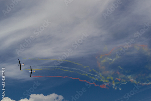 two planes leave stripes of colored smoke behind them against the sky