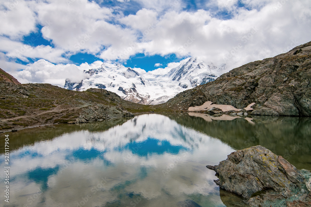 Monte Rosa (Dufourspitze) and Lyskamm covered by clouds and reflected on the Riffelsee, Swiss Alps, Valais, Switzerland