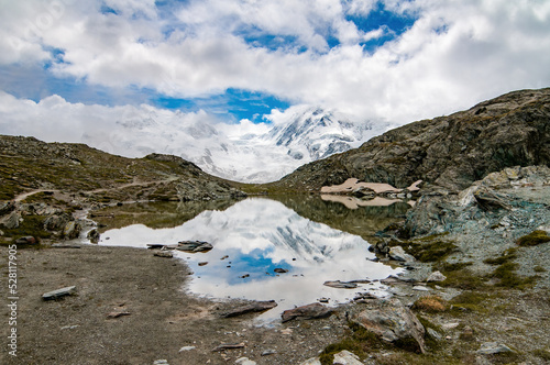 Monte Rosa (Dufourspitze) and Lyskamm covered by clouds and reflected on the Riffelsee, Swiss Alps, Valais, Switzerland