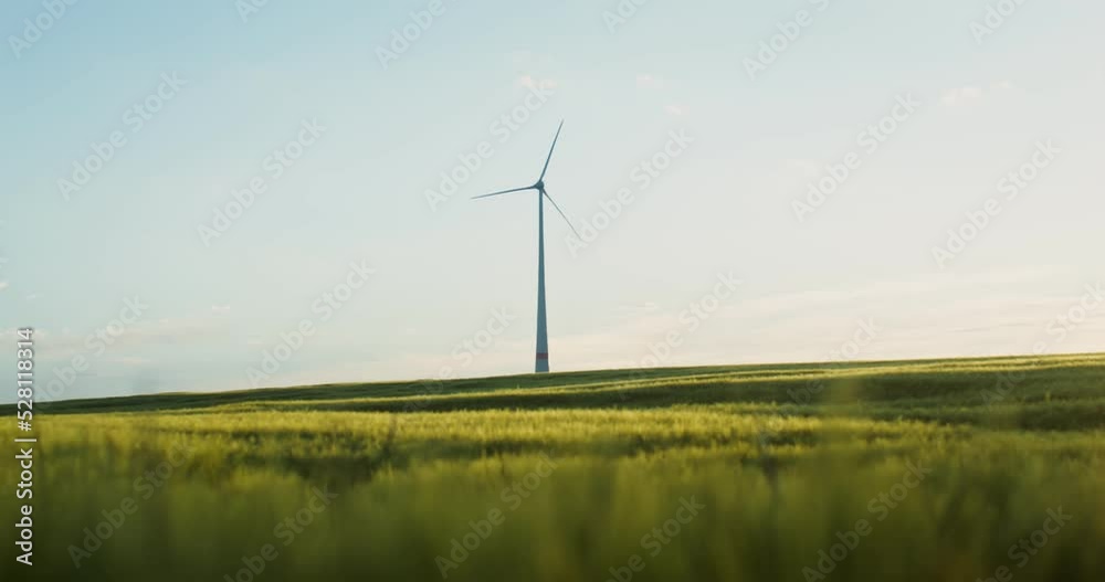 The wind generator stands in the middle of a picturesque green field with dense tall grass. Video filming on a summer sunny day. Beautiful landscape of the countryside. 4k video, red komodo The wind generator stands in the middle of a picturesque green field with dense tall grass. Video filming on a summer sunny day. Beautiful landscape of the countryside. 4k video, red komodo