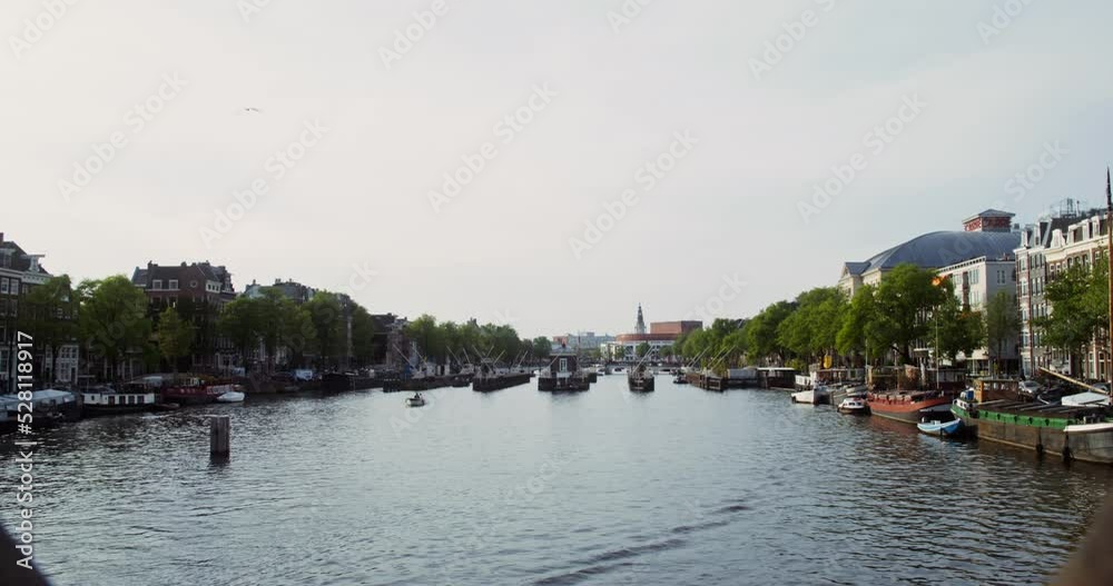 Panoramic view of a beautiful European city with traditional houses on both sides of the canal. Many ships are moored along the banks of the canal. Amsterdam, Netherlands. Video in 4k, red komodo