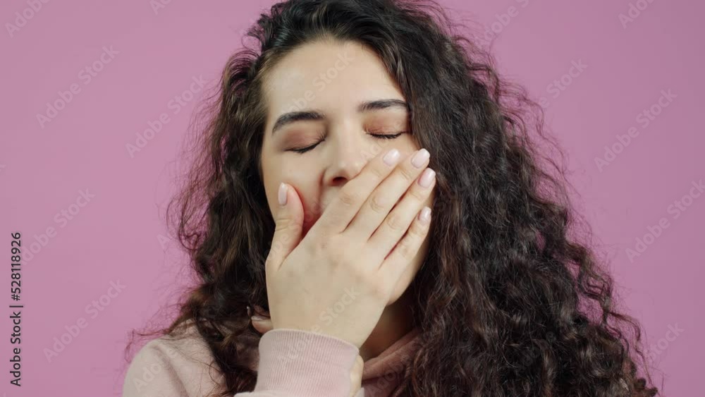 Close-up portrait of sleepy young woman yawning and rubbing face on pink color background. Expressions and millennials concept. Close-up portrait of sleepy young woman yawning and rubbing face on pink color background. Expressions and millennials concept.