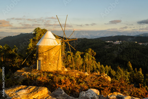 Windmill in the rays of the setting sun. Beautiful sunset in the mountains in rustic style