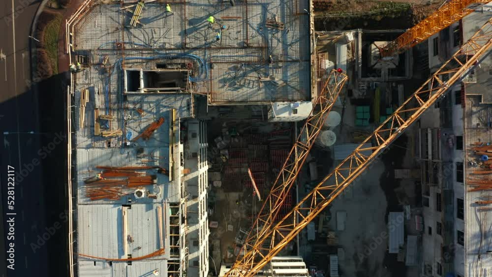 Drone shot on the construction of a new residential building. Construction site with cranes and construction workers with heavy machinery. Drone shot on the construction of a new residential building. Construction site with cranes and construction workers with heavy machinery.
