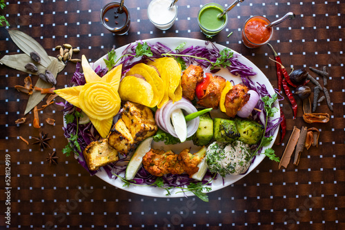 Mixed kabab platter with seekh kabab, tikka, haryali kabab boti raita, mint, sauce, chutney and ketchup served in a dish isolated on table background top view of bangladesh food photo