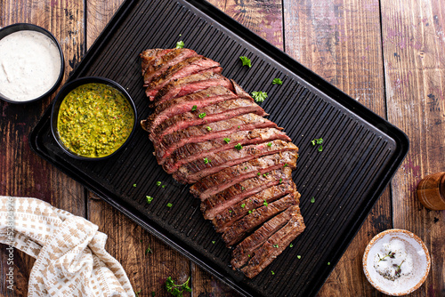 Seared flank steak on a grill pan with chimichurri and horseradish