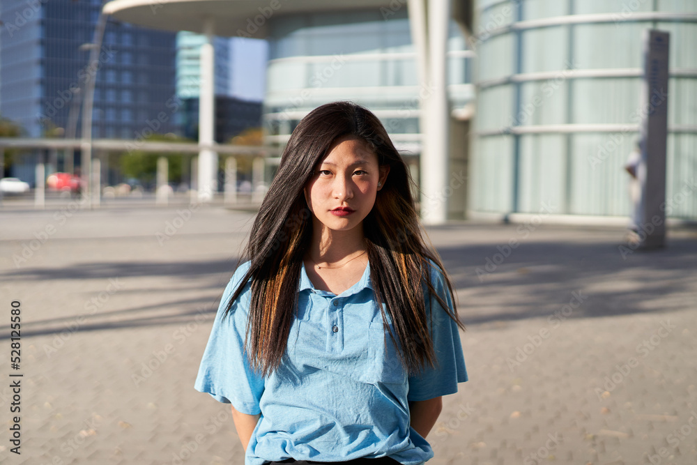 Serious asian Student. Chinese girl looking at the camera outdoors on campus of university. Ethnicity people. Serious asian Student. Chinese girl looking at the camera outdoors on campus of university. Ethnicity people.