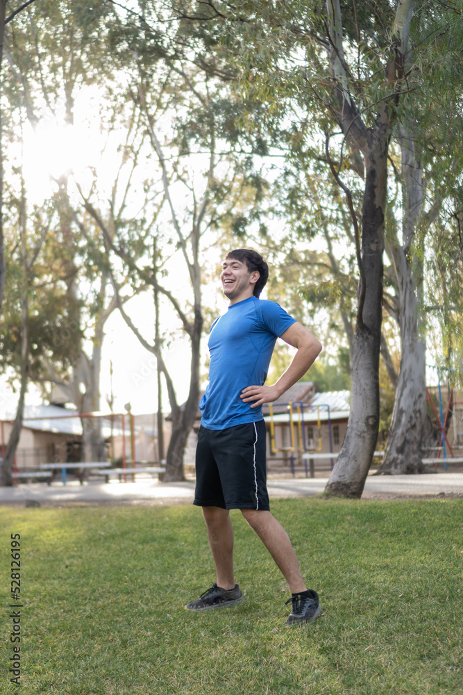 smiling young man in blue T-shirt stretching smiling young man in blue T-shirt stretching