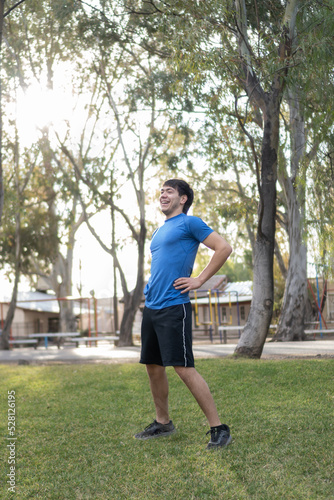 smiling young man in blue T-shirt stretching