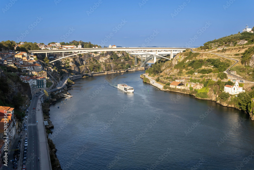 A view of the Douro River with a sailing cruise ship and the bridges in Porto