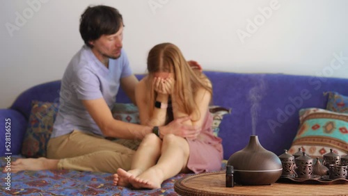 A young woman is in stress, her partner is trying to comfort her. The aroma lamp is in the foreground. Aromatherapy can releave bad emotions. Electric Ultrasonic Essential Oil Aroma Diffuser and photo
