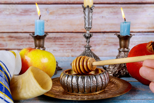 Jewish New Year symbolism with shofars, honey jars and fresh apples pomegranates in celebration of Rosh Hashanah holiday photo