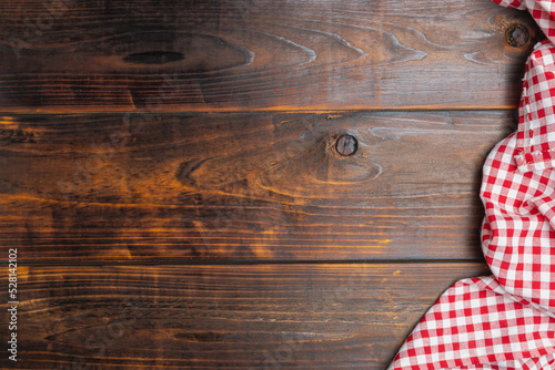 Tablecloth red and white checkered squared on old wooden, top view. With copy space for design menu of food for restaurant. Fabric texture background. Texture of cotton fabric.