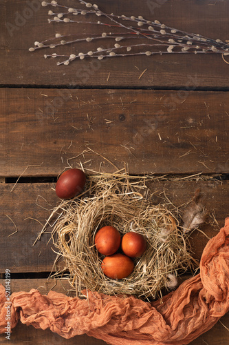 Painted Easter chicken eggs in a nest and willow branches. Holiday Easter concept background. High quality photo