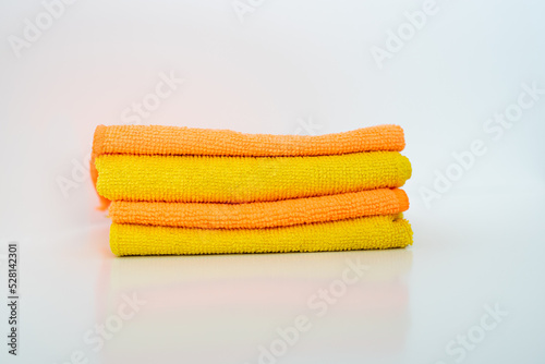 Four yellow-orange microfiber napkins are stacked on a white background. Home cleaning tool. photo