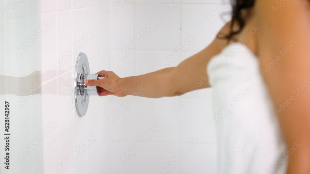 Close-up of a woman's hand turning on the shower before entering.