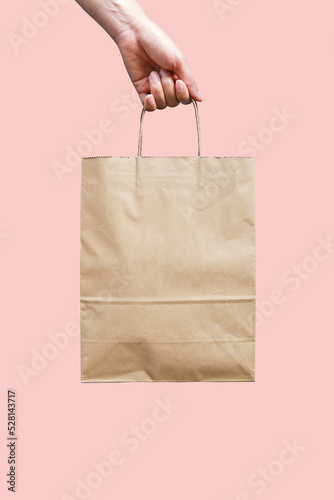 Woman's hand holding an empty brown paper bag. Packaging template mock up. Recycled, eco friendly, and shopping concept