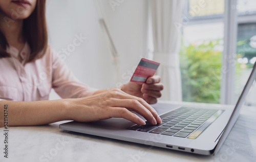 Woman hand holding credit card and using laptop at cafe for paying online using internet banking service. Online shopping concept
