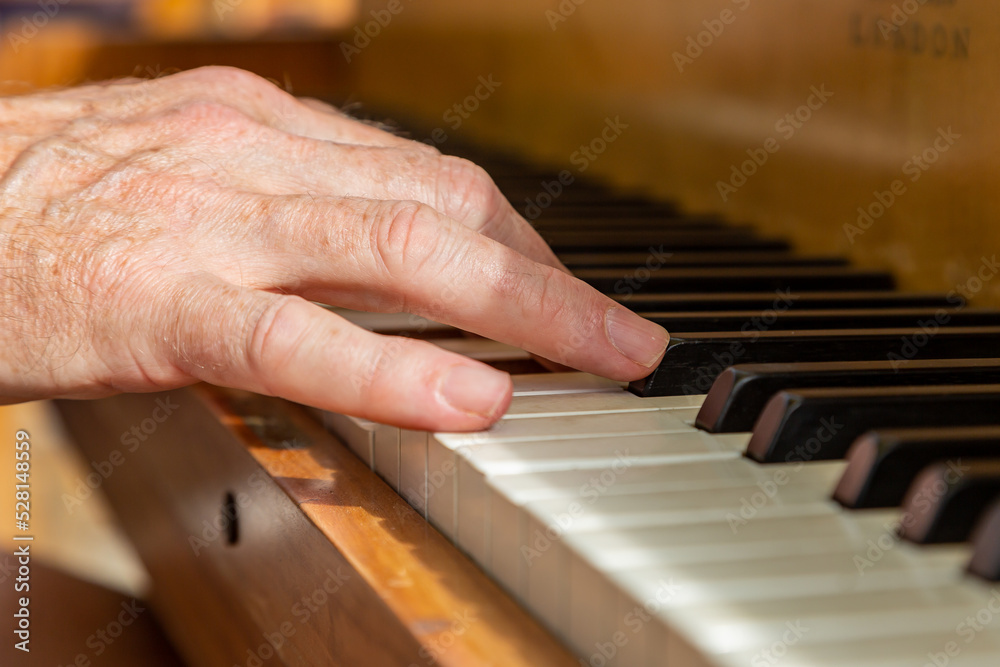 A mans hands playing a piano, with selective focus