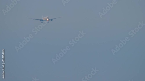 Footage long shot of a passenger airliner descending for landing at dusk. Airplane in cloudy sky, front view. Tourism and aviation concept photo