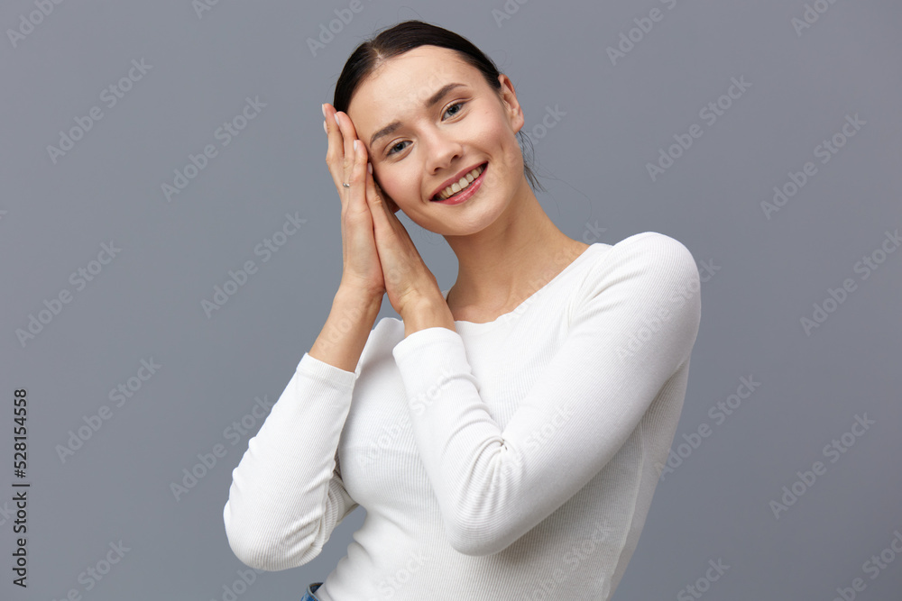 a gentle woman stands on a dark background in a tight white T-shirt, raised her hands, gently touching her head to her fingers a gentle woman stands on a dark background in a tight white T-shirt, raised her hands, gently touching her head to her fingers