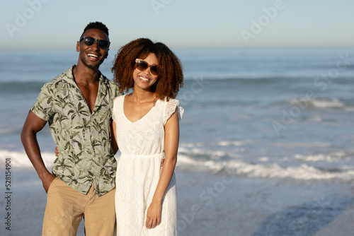 A mixed race couple posing and smiling on beach on a sunny day 