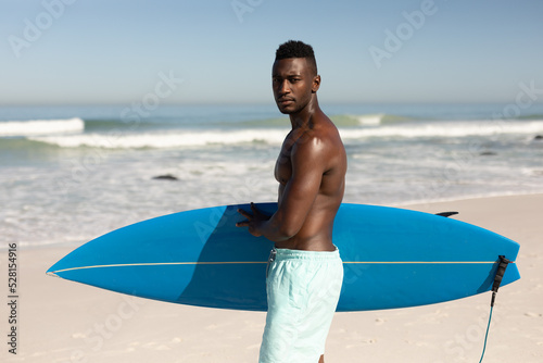 Canvas Print African American man holding surf board on the beach