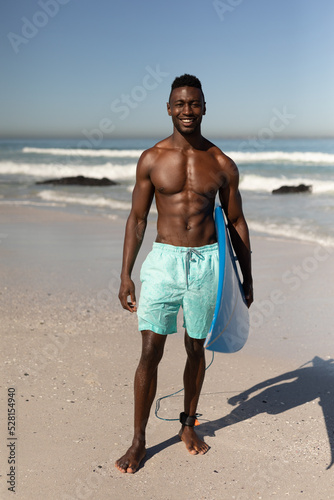 African American man holding surf board on the beach