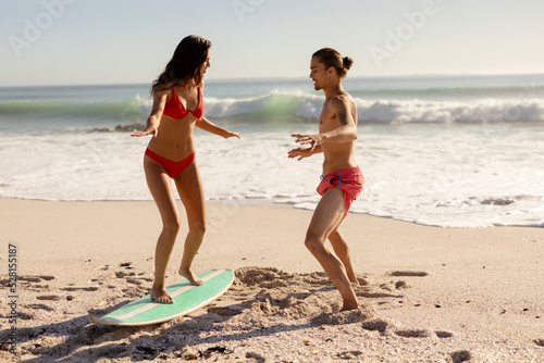 Young mixed race people practising surf on beach