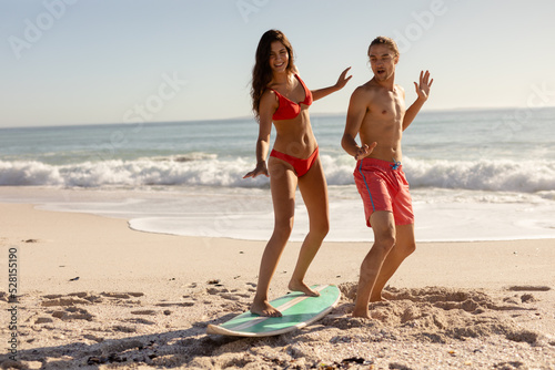 Young mixed race people practising surf on beach