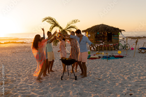 Mixed race friends doing barbecue and drinking alcohol on beach