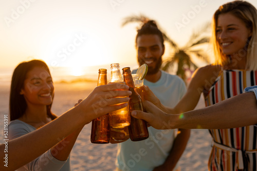 Mixed race friends drinking beer on beach