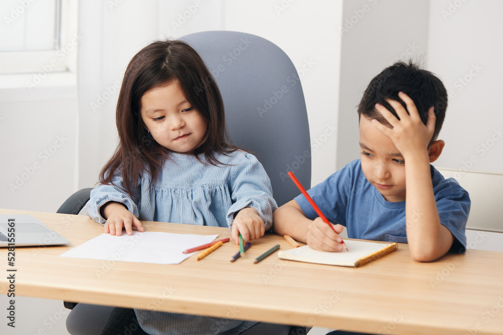 cute little kids sitting drawing with pencils at the table during class cute little kids sitting drawing with pencils at the table during class