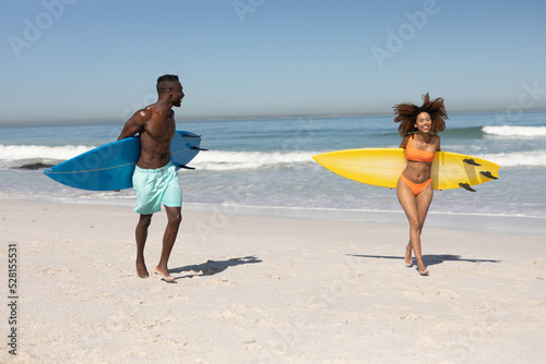 Happy couple holding surfboards on the beach