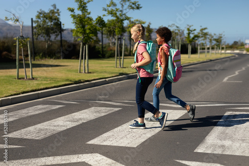 Fotografering Schoolgirls crossing the road on a pedestrian crossing