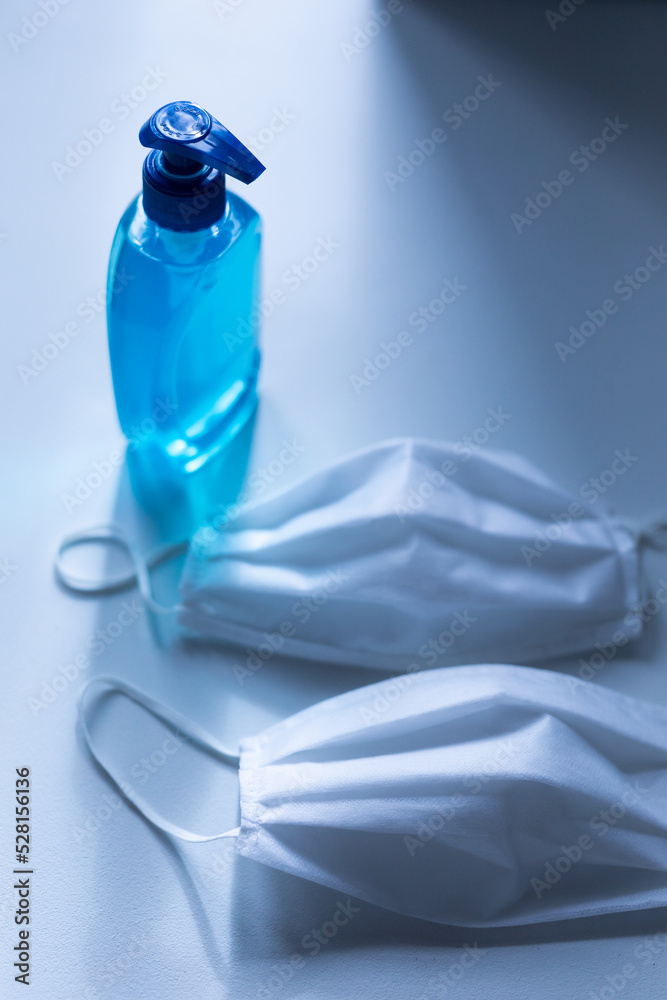 Fototapeta premium Close up of a sanitizer and two white face masks for protection against coronavirus covid 19 epidemi