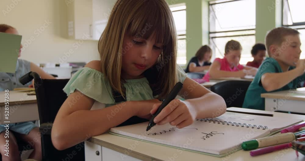 Physically challenged girl writing in her notebook in the class Physically challenged girl writing in her notebook in the class