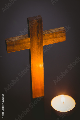 Lit candle by wooden cross