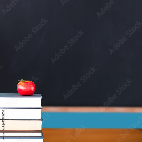 Red apple on pile of books in classroom