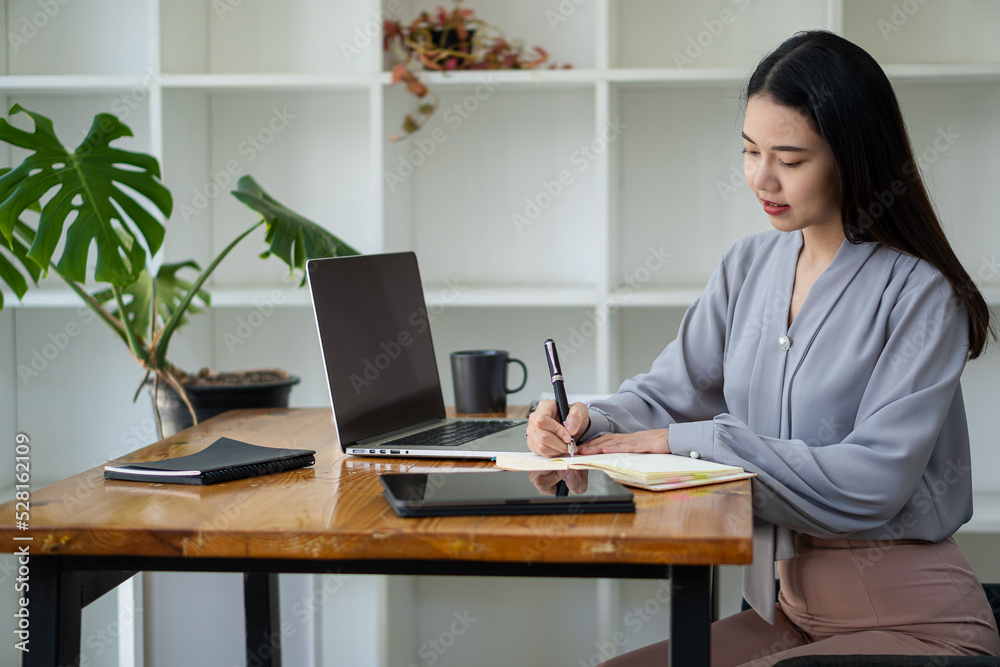 Asian woman working in office with laptop and tablet online working concept