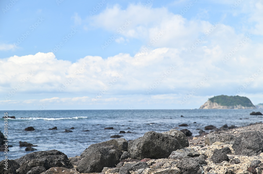 There are rocks and after that we can see the sea and island There are rocks and after that we can see the sea and island