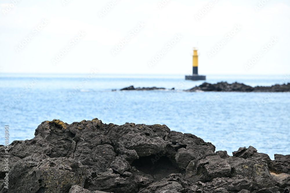 You can see the rocks on the beach and the lighthouse behind them